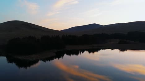 Water-symmetry-moving-shot-of-sunrise-between-mountains-in-Ireland