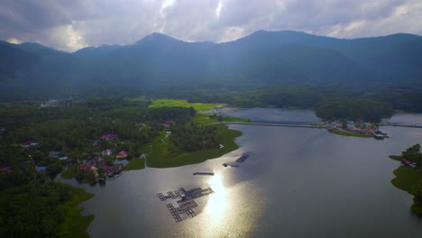 Aerial-Shot-of-Raban-Lake-with-Mountain,-Fish-Farm-and-Forrest-during-beautiful-Sunset-with-God-Ray,-Malaysia