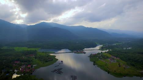 Aerial-Shot-of-Raban-Lake-with-Mountain,-Fish-Farm-and-Forrest-during-beautiful-Sunset-with-God-Ray,-Malaysia