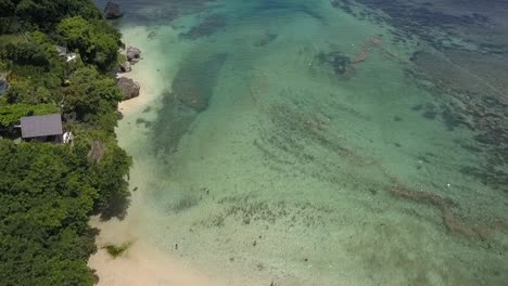 Playa-De-Padang-Padang,-Drone-Volando-Sobre-La-Playa-Hacia-El-Mar-De-Agua-Esmeralda,-Bali-indonesio,-Agua-Cristalina