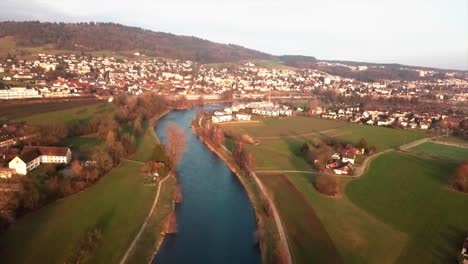 Aerial-drone-shot-flying-forwards-above-the-river-Limmat-and-revealing-the-town-of-Unterengstringen-in-the-background-in-the-canton-of-Zürich,-Switzerland