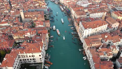 En-Venecia,-Italia,-Una-Panorámica-Lenta-Hacia-Arriba-Mientras-El-Dron-Avanza-Sobre-El-Gran-Canal-Y-Revela-El-Puente-De-Rialto
