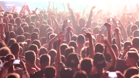 Fans-waving-their-hands-and-filming-by-phones-crowd-at-a-concert-partying-at-a-night-club-with-DJ-performing-on-stage