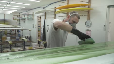 slow-motion-surfboard-being-glassed-and-painted-with-squeegee