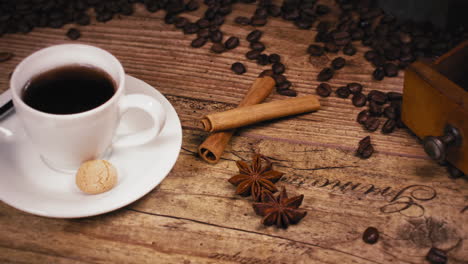 Close-shot-of-a-delicious-small-coffee-with-cinnamon,-star-anise-and-coffee-beans-on-a-wooden-table