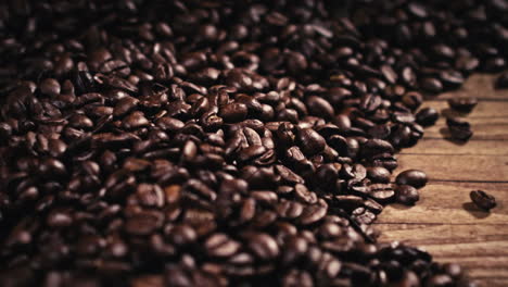 Slow-motion-shot-of-coffee-beans-dropping-on-a-wooden-table