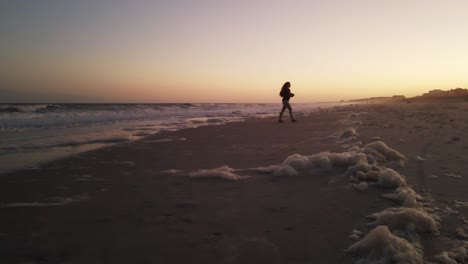 Wide-Shot-Silhouette-Eines-Mädchens,-Das-Während-Des-Sonnenuntergangs-Fotos-Am-Strand-Macht