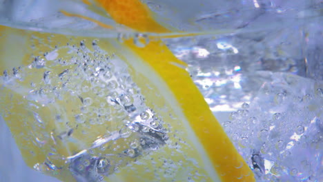 Extreme-Close-up-of-a-tasty-lemon-slice-in-a-jar-of-sparkling-water-with-ice-cubes-slowly-moving-around