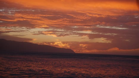A-stunning-sunset-over-Oahu-Hawaii-North-Shore-Kaena-Point-in-orange-and-purple-with-rolling-waves