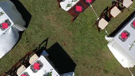 Drone-shot-over-tables-laid-for-wedding-dinner-supper-meal-in-hawaii-outdoors-with-lighting-and-wind-blowing-white-table-cloths