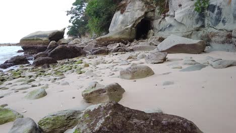 Moving-across-a-rocky-beach-towards-a-mysterious-cave-with-sprawling-forest-around-and-the-andaman-sea-to-the-left