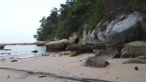 A-long-piece-of-wood-has-been-washed-up-on-a-remote-beach-in-the-Andaman-islands-where-giant-boulders-have-fallen-and-forest-lines-the-shore