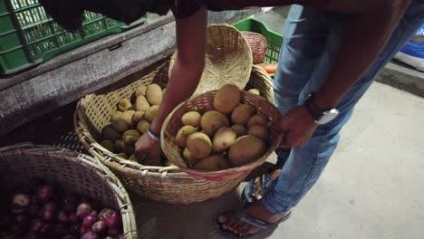 A-man-a-the-market-picks-out-potatoes-from-his-main-basket-into-a-smaller-basket-for-his-client