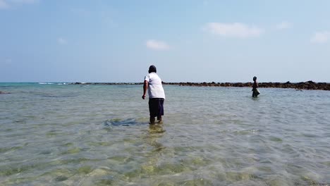 two-fishermen-on-a-windy-day-in-the-andaman-islands-standing-leg-deep-in-water-catching-their-food-for-their-families-with-lines-and-hooks-in-the-midday-sun