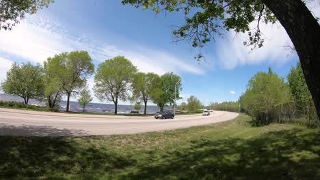 Timelapse-at-a-waterfont-on-a-blye-sky-day-with-many-cyclists-and-cars-going-by-really-fast
