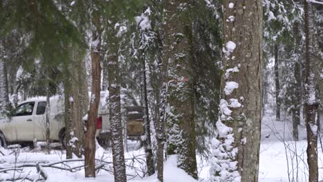 white-SUV-pulling-a-small-trailer-trough-a-snowy-evergreen-forest-in-Latvia,-Northern-Europe