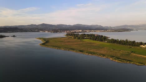 Aerial-sideways-drone-shot-flying-past-Rapperswil-and-Hurden-during-a-summer-sunset