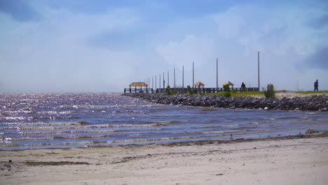 People-walking-with-fishing-gear-on-a-stone-pier-on-a-beautiful-sunny-day-in-coastal-mississippi