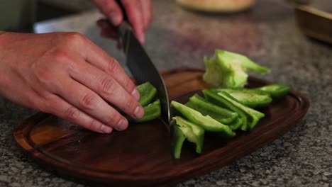 Chopping-a-green-bell-pepper-on-a-wooden-cutting-board