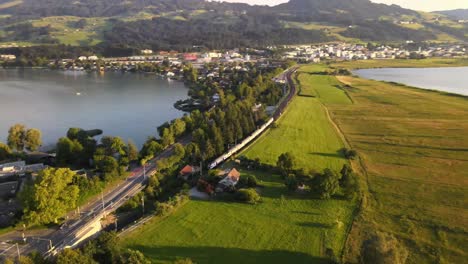 Aerial-drone-shot-showing-SBB-train-driving-towards-Rapperswil-on-a-summer-evening
