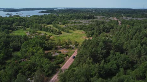 Car-driving-in-Brando-Island-in-the-middle-of-woods-in-Aland-Islands,-Finland,-aerial-following-shot