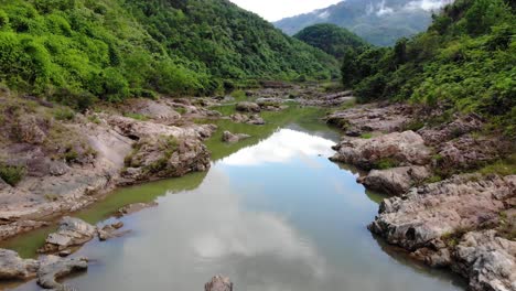 Fast-Aerial-Dolly-forward-over-river-in-the-middle-of-a-valley-at-Quang-Nam-Province,-Vietnam