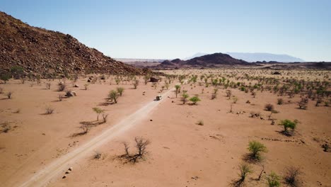 Aerial-pan-reveals-offroad-vehicle-exploring-unforgiving-desert-landscape