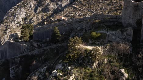 AERIAL---Ancient-city-walls-of-Kotor,-Montenegro,-a-World-Heritage-Site,-reverse