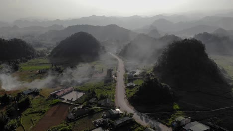 Aerial-Dolly-in-over-a-village-road-surrounded-by-mountains-and-fields,-Ha-Giang,-Vietnam