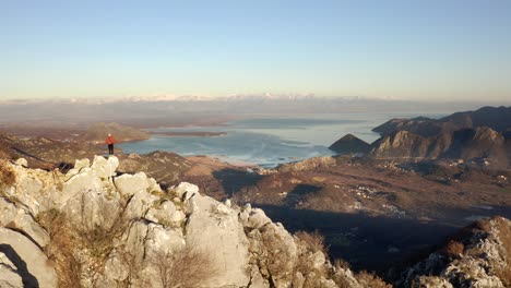 AERIAL---Person-hiking-in-mountains-around-Lake-Skadar,-Montenegro,-pan-left-reveal