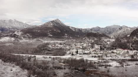 AERIAL---Snowy-village-of-Virpazar-and-mountains,-Bar,-Montenegro,-forward