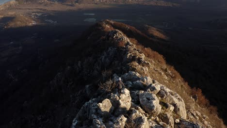 AERIAL---Person-hiking-in-mountains-around-Lake-Skadar,-Montenegro,-forward-tilt-up