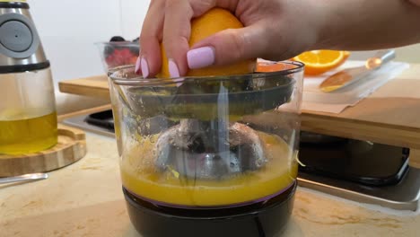 Close-up-of-female-hand-squeezing-fresh-orange-using-juice-squeezer,-healthy-Breakfast