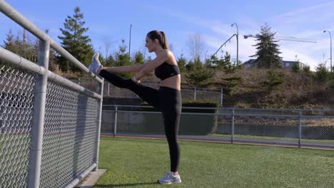 Flexible-Athletische-Junge-Frau,-Die-Bein-Gegen-Geländer-Streckt