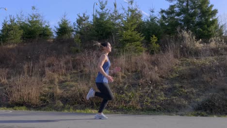 Fit-woman-out-running-along-road-tracking-shot
