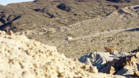 Ein-Freizeitfahrzeug-Fährt-Auf-Dem-Weg-Zu-Einem-Campingplatz-Durch-Die-Zerklüftete-Landschaft-Der-Mojave-Wüste-Im-Red-Rock-Canyon-State-Park
