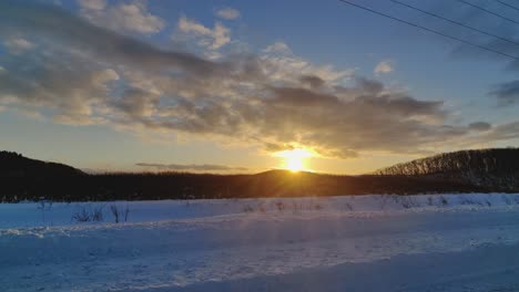 Driving-Past-Golden-Yellow-Sunset-In-Snow-Winter-Landscape-Road-In-Hokkaido