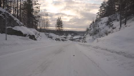 Winter-Landscape---Dirt-Road-In-The-Forest-Covered-In-Snow-During-Sunset---aerial-low