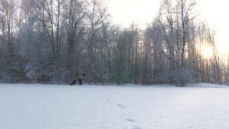 Man-walks-with-wide-strides-in-snow-filled-field