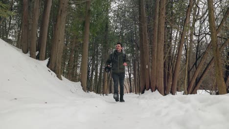 Low-Static-shot-of-Hiker-in-Dense-Snow-Covered-Winter-Forest-Walking-towards-camera