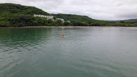 Aerial-dolly-out-of-people-doing-kayaking-near-Planet-Hollywood-hotel-between-woods,-Nacascolo-beach,-Papagayo-Peninsula,-Costa-Rica