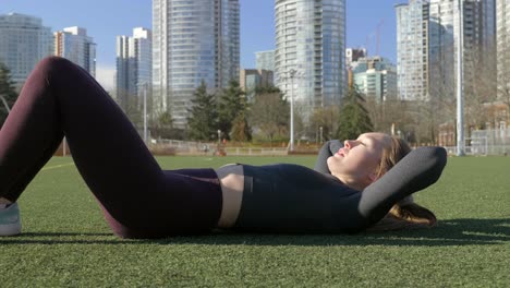 Young-athletic-woman-doing-ab-crunches-in-park