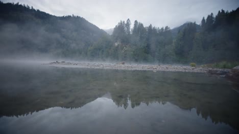 Dolly-shot-lake-covered-in-misty-fog-at-dawn-or-dusk