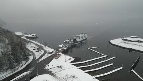 A-Washington-State-Ferry-slowly-pulls-into-its-moor-during-a-snowstorm,Tacoma,-aerial