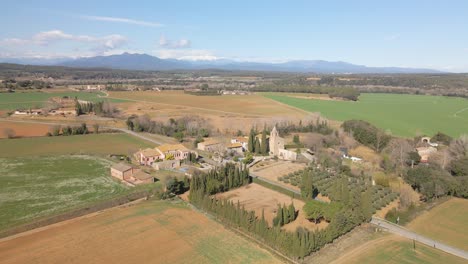 Aerial-view-of-nature-sown-field-without-people-Snowy-Pyrenees-mountain-in-the-background-Small-town-in-Catalonia