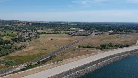 Aerial-view-of-cars-driving-on-the-highway-next-to-Folsom-lake-shoreline