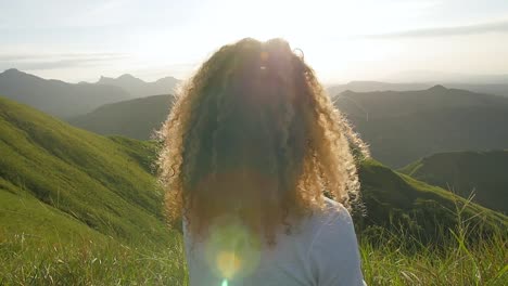 Young-Latin-American-male-with-curly-blonde-hair-observing-a-sunset-at-a-volcano-wall-summit-in-Valle-de-Anton-Panama,-Pan-right-shot
