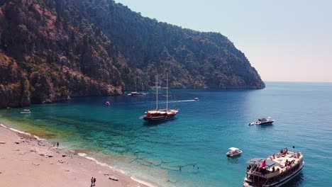 Aerial-dolly-shot-of-paradisiacal-sandy-beach-in-Turkey-with-boats-anchored-in-the-turquoise-sea
