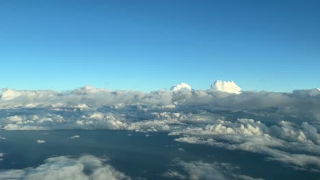 Aerial-view-from-a-cockpit-overflying-few-clouds-with-a-deep-blue-sky