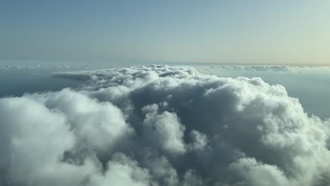 Aerial-view-from-a-cockpit-overflying-few-clouds-with-afternoon-light-over-the-sea